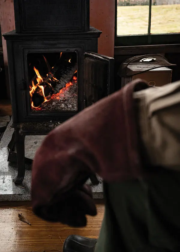 Joseph Monninger tends to the woodstove in his Pembroke Maine cabin