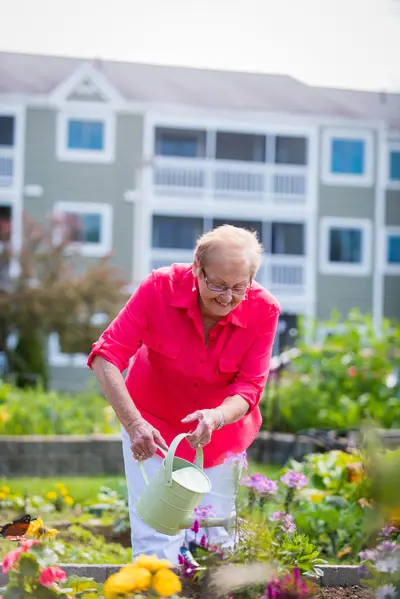 a woman watering the garden at the Highlands in Topsham, Maine