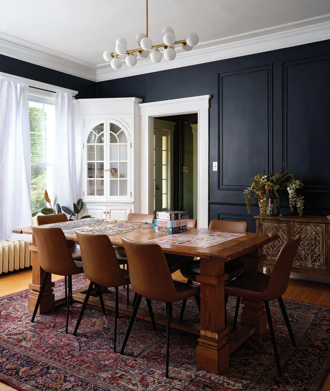 Behr’s Midnight Blue on the walls and a Sofary globe chandelier provide modern counterpoints in the otherwise historic looking dining room