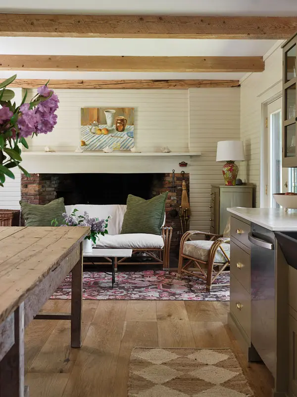 the kitchen nook includes another replica Colonial fireplace, heirloom rattan furniture, and an area rug
