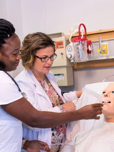 a University of Maine at Fort Kent nursing student and instructor practice on a medical dummy